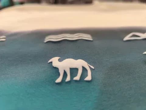 Textile print with camel and wave motifs on gradient fabric.