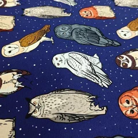 Fabric featuring multicolored owl illustrations on dark blue